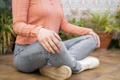 Frau meditiert im Schneidersitz im Garten, lizenzfreies Stockfoto