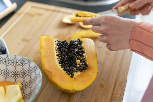 Woman cutting papaya in kitchen at home - AFVF08289