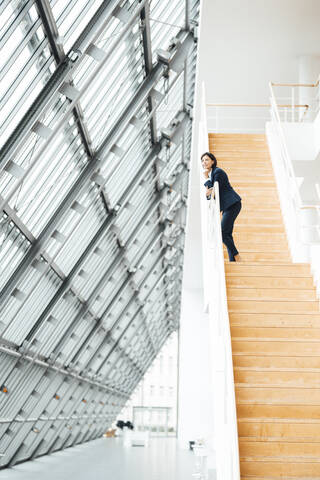 Unternehmerin steht auf einer Treppe im Korridor, lizenzfreies Stockfoto