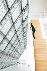 Unternehmerin steht auf einer Treppe im Korridor - JOSEF03624
