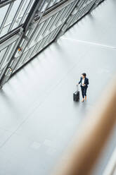 Businesswoman with suitcase walking in corridor - JOSEF03658
