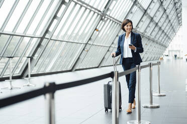 Mature businesswoman with suitcase walking in corridor - JOSEF03662