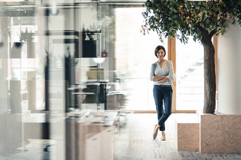 Confident female entrepreneur with arms crossed in office stock photo