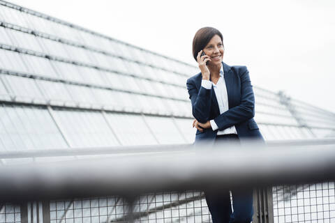 Female entrepreneur talking on smart phone outside office building stock photo