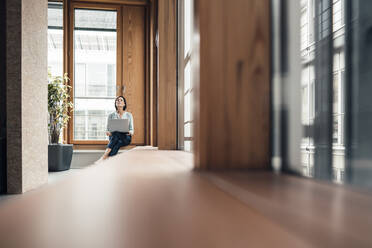 Weibliche Unternehmerin mit Laptop sitzt auf Nische Witwe Sitz im Büro - JOSEF03709