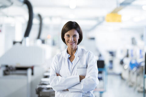 Mature female technician with arms crossed in industry stock photo