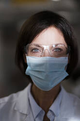 Female scientist with protective eyewear at laboratory during pandemic - JOSEF03724