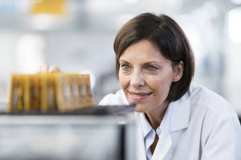 Smiling female technician examining equipment at factory - JOSEF03726