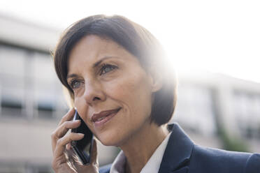 Mature businesswoman talking on smart phone outdoors - JOSEF03741