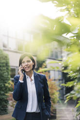 Female professional talking on smart phone at office park - JOSEF03743