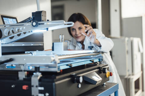 Mature female technician analyzing machinery at industry stock photo