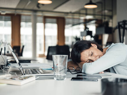 Businesswoman with head down relaxing on desk at office - JOSEF03760