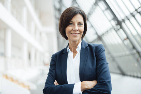 Confident female professional with arms crossed in corridor stock photo