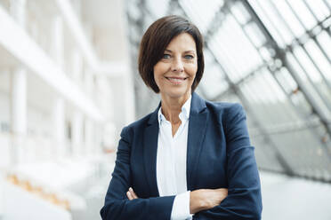 Confident female professional with arms crossed in corridor - JOSEF03766