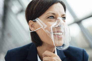 Mature businesswoman with protective face shield at office - JOSEF03774