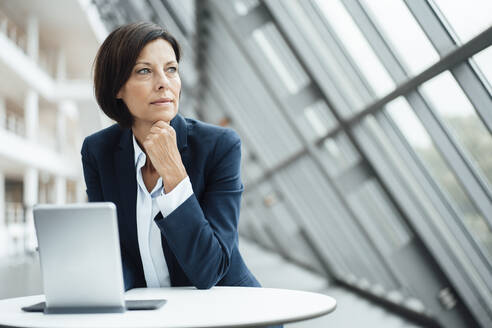 Female professional contemplating by digital tablet in corridor - JOSEF03778