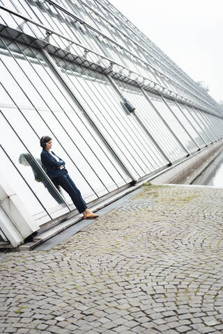 Female professional leaning against wall at lakeshore stock photo