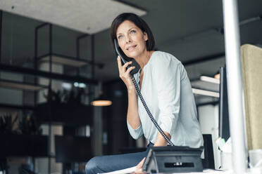 Reife Geschäftsfrau im Gespräch über das Festnetztelefon im Büro - JOSEF03821