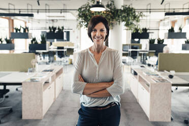 Confident businesswoman with arms crossed standing in office - JOSEF03826