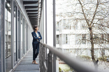 Mature businesswoman with arms crossed on office balcony - JOSEF03830