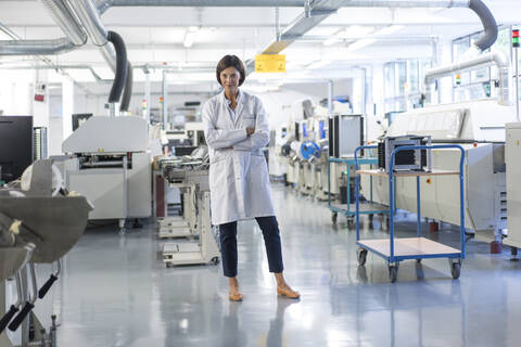 Selbstbewusste Ingenieurin mit verschränkten Armen in der Industrie stehend, lizenzfreies Stockfoto