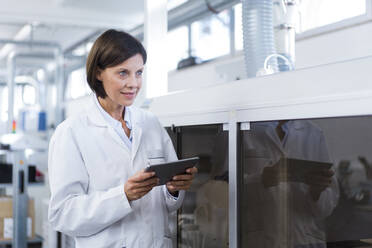 Female technician with digital tablet looking away at factory - JOSEF03874