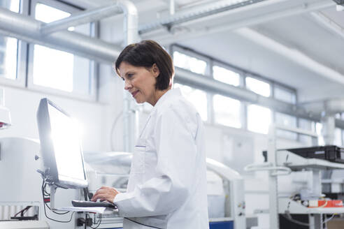 Female technician working on computer at factory - JOSEF03879