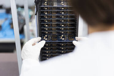 Female engineer inserting circuit board in machinery at factory - JOSEF03892