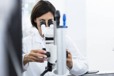 Female scientist using microscope at laboratory - JOSEF03893