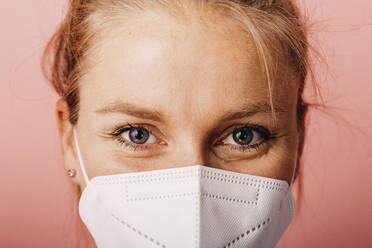 Close-up of woman wearing protective face mask against colored background - DAWF01786