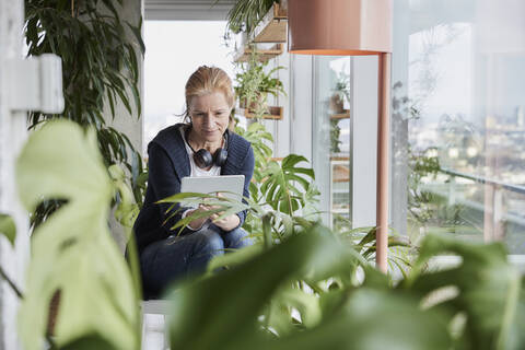 Woman using digital tablet while sitting in loft apartment at home stock photo