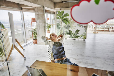 Lächelnde Geschäftsfrau entspannt durch Glaswand im Büro gesehen, lizenzfreies Stockfoto