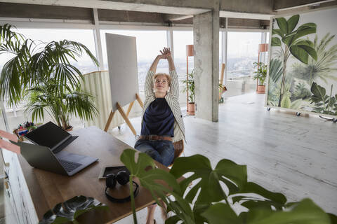 Unternehmerin entspannt sich am Schreibtisch im Büro, lizenzfreies Stockfoto