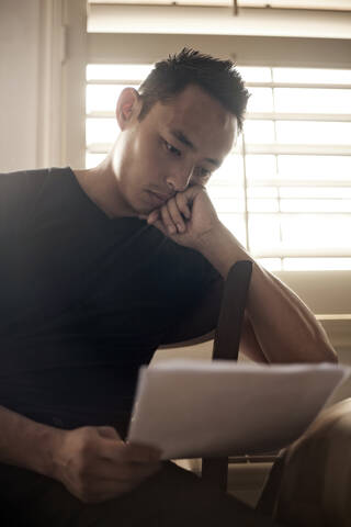 Man reading letter while sitting at home stock photo