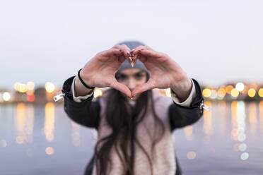 Teenage girl doing heart with her hands during sunset - JRVF00290