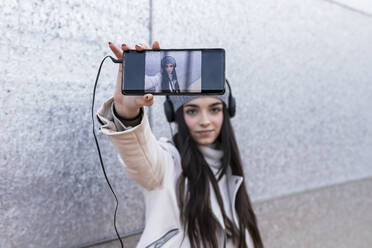 Teenager-Mädchen nimmt Selfie durch Smartphone beim Hören von Musik - JRVF00310