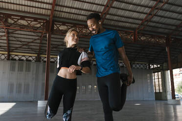 Male and female athletes doing warm up exercise in health club - EGAF01871