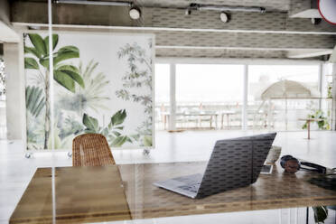 Laptop on table in apartment seen through glass wall - FMKF07032