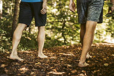 Männer in kurzen Hosen gehen im Wald spazieren - DAWF01831