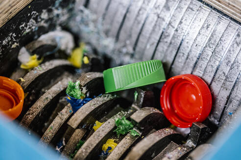 Plastic bottle caps being recycled in machinery - DAWF01835