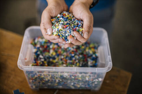 Man with container holding recycled plastic in factory - DAWF01837