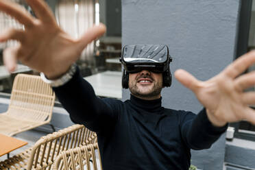 Geschäftsmann benutzt ein Virtual-Reality-Headset, während er in einem Café sitzt - EGAF01912