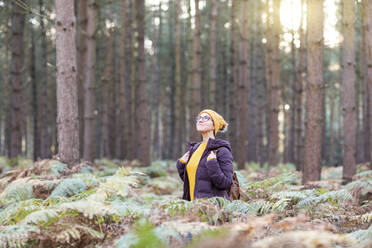 Frau schaut nach oben, während sie im Herbst den Wald erkundet - WPEF04195