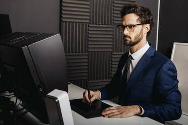 Businessman using graphic tablet at desk in office - DAWF01870