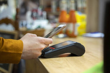 Frau benutzt Smartphone zum kontaktlosen Bezahlen an der Kasse eines Lebensmittelgeschäfts - AFVF08315