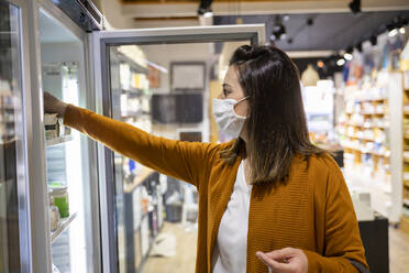 Junge Frau greift nach Lebensmitteln im Kühlschrank eines Geschäfts - AFVF08319