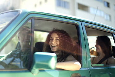 Lächelnde Frau schaut weg, während sie mit Freunden im Auto sitzt - AJOF01126