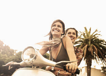 Lächelnde Frau genießt Rollerfahrt mit Freund - AJOF01130