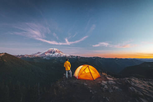 Ein Mann steht bei einem Zelt auf dem Gipfel eines Berges in der Nähe des Mount Rainier - CAVF93479