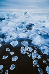 Long exposure of water running through ice blocks on black sand beach - CAVF93484